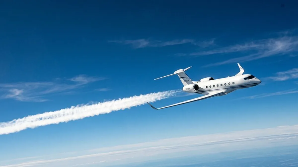Business jet bianco in salita davanti a un cielo blu con scia di condensazione